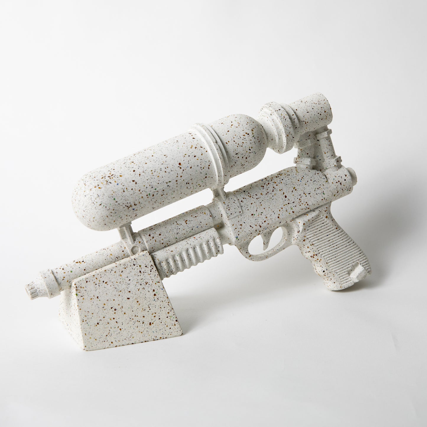 The Ultra Sprayer Sculpture in White Terrazzo, resting on a stand.
