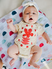 Flowers Onesie on Charli in Cream w/ Red/Orange.