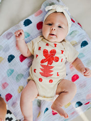 Flowers Onesie on Charli in Cream w/ Red/Orange.