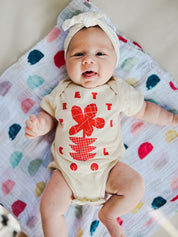 Flowers Onesie on Charli in Cream w/ Red/Orange.