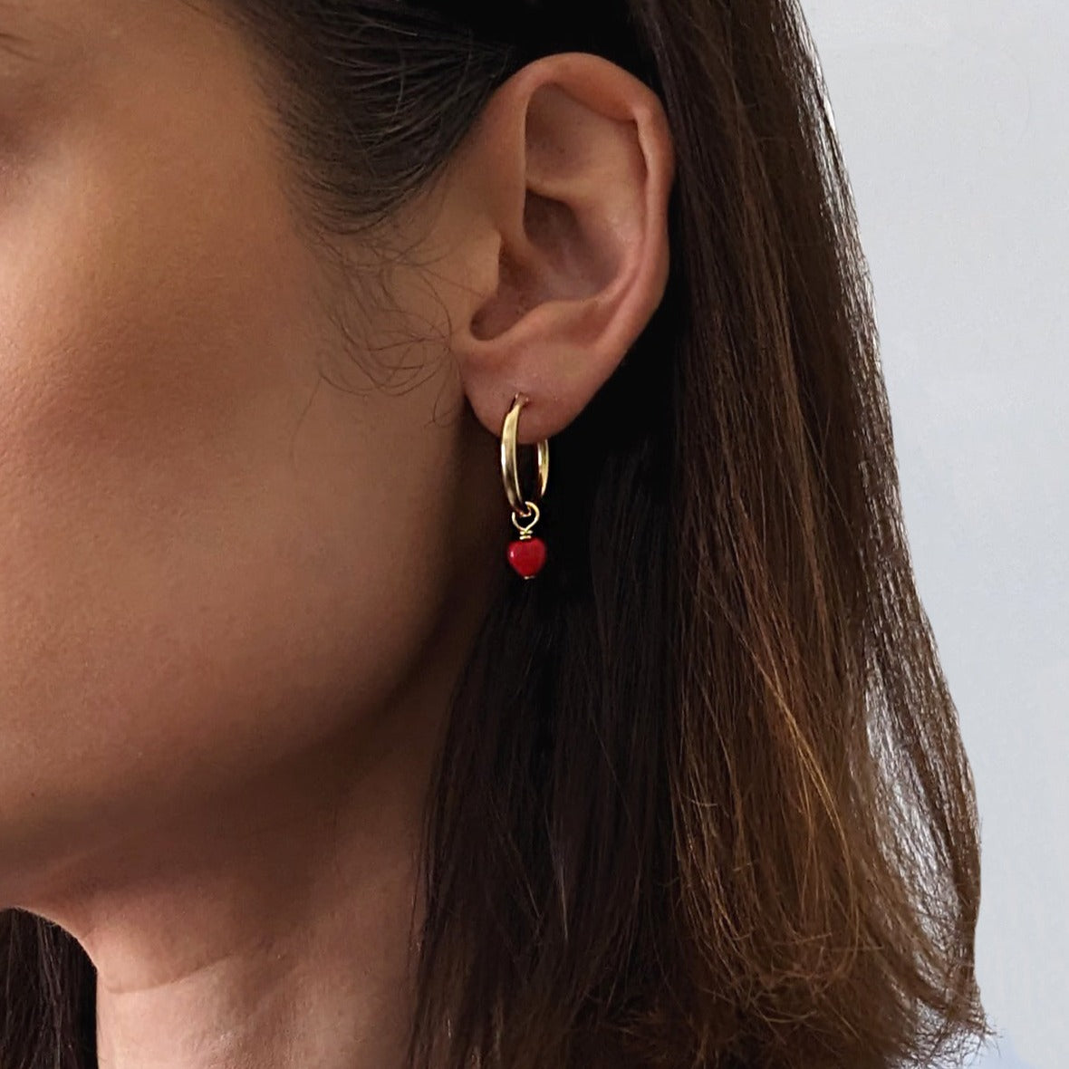 Gold Fill Heart Charm Hoop Earrings on a model.