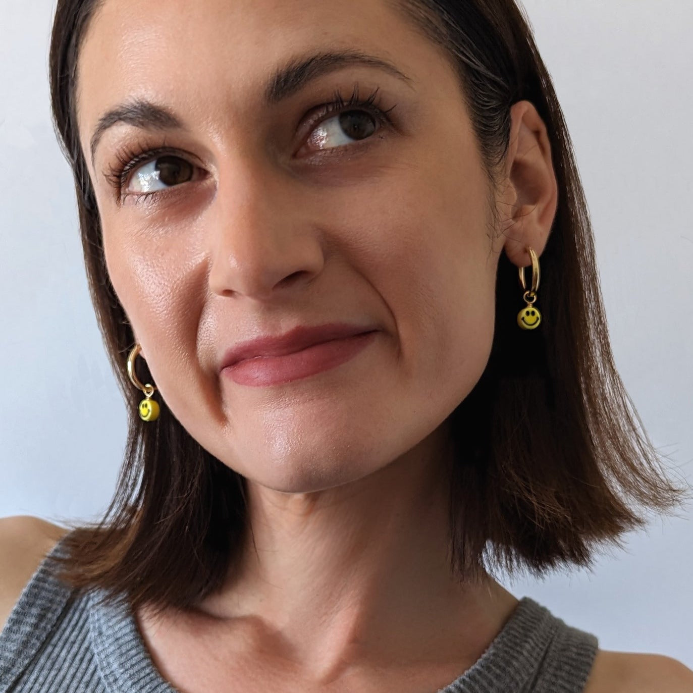 Gold Fill Smiley Charm Hoop Earrings on a model.