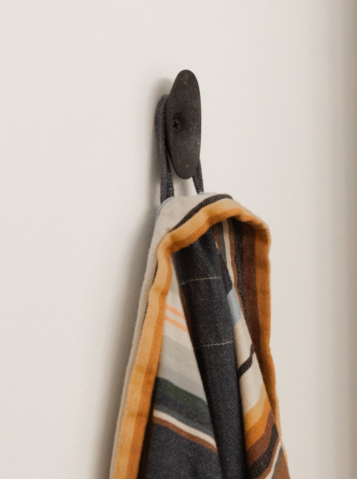 Black terrazzo coat hook, styled with a robe hanging from it.