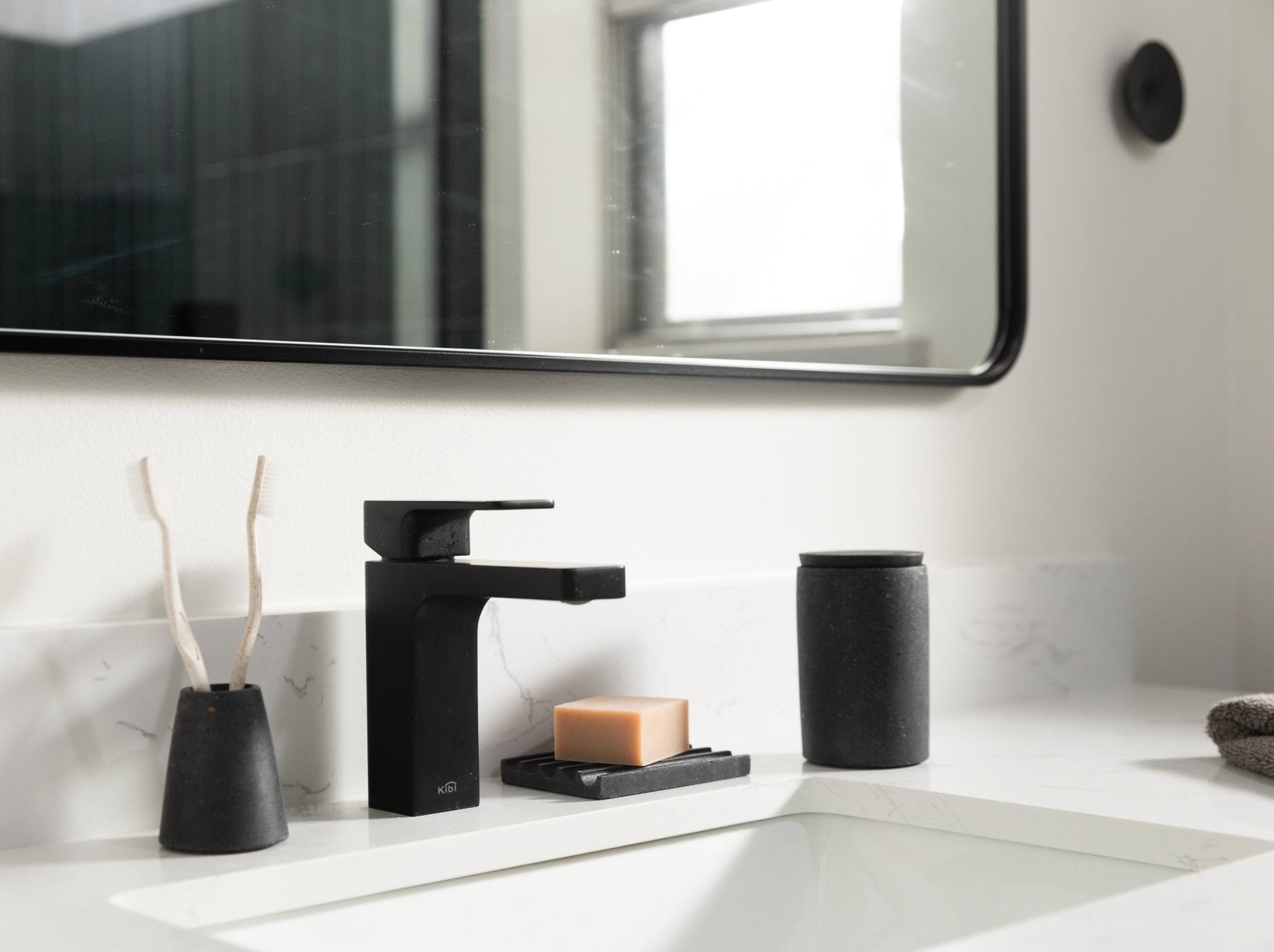Toothbrush Holder, Soap Dish, Cotton Swab Holder, & Wall Hook in Black Terrazzo, styled by a sink.