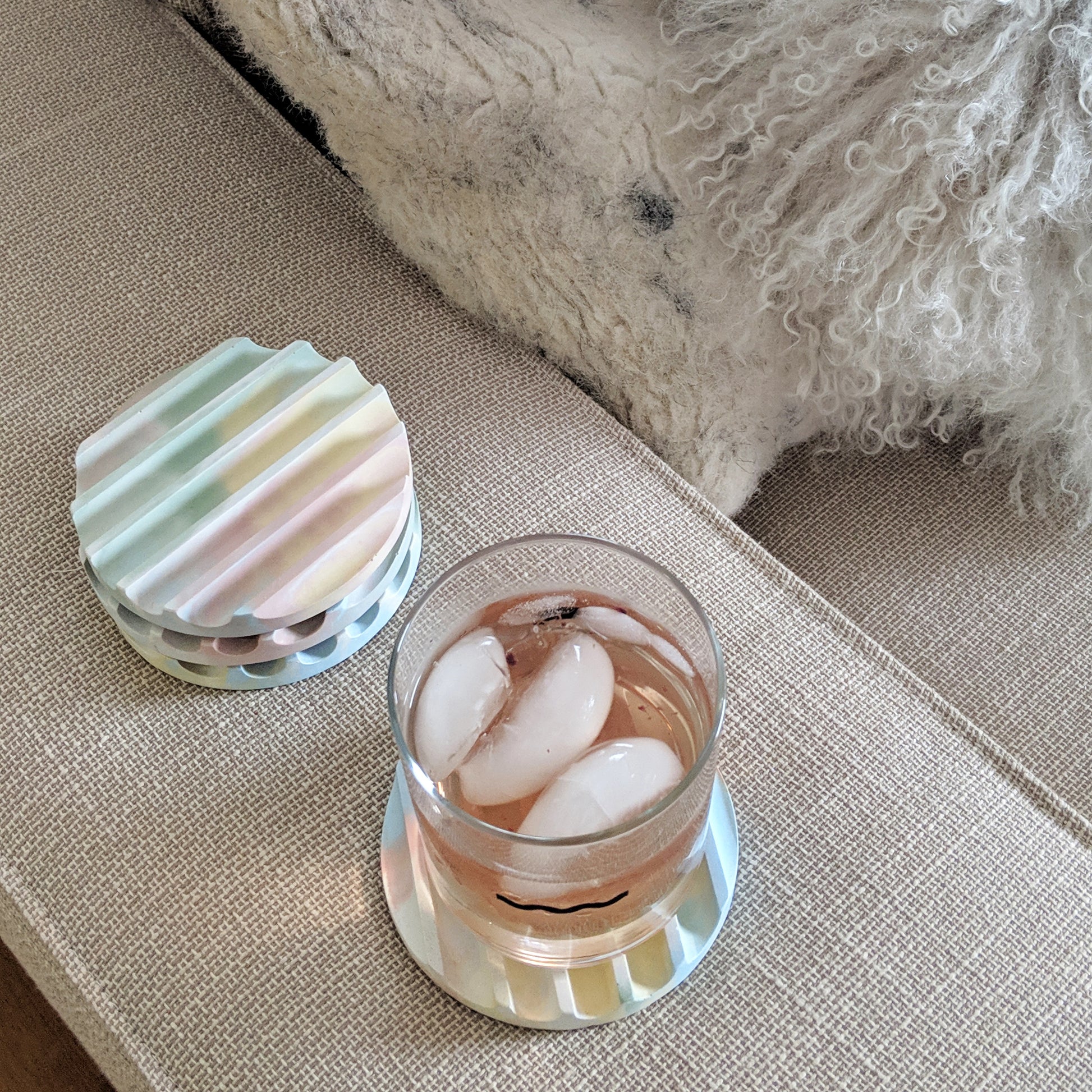 Concrete coaster set with cork base in jawbreaker (multicolor) shown with drink.