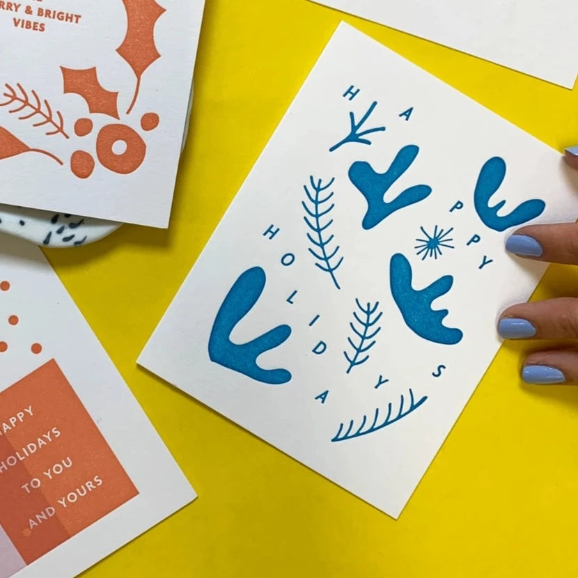 Meshworks Press Happy Holidays Snowprints Card, next to a hand for scale