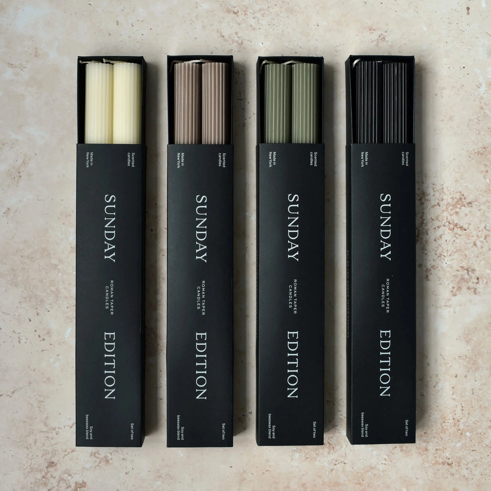 Sunday Edition's Roman Taper Candles in multiple colors in their packaging.