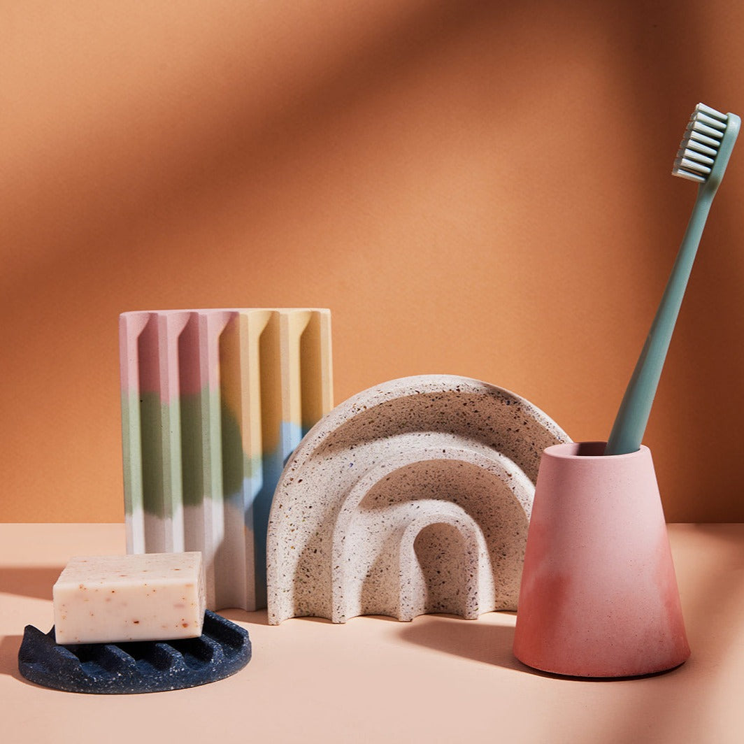 An assortment of pretti.cool products, including the cobalt terrazzo mini soap dish, jawbreaker soap dish, white terrazzo sponge rest, and pink & coral toothbrush holder.