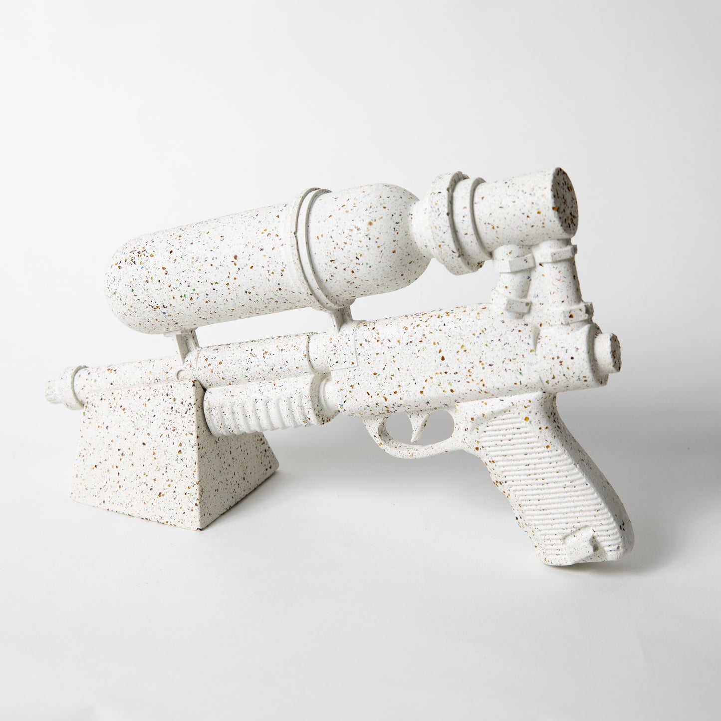 The Ultra Sprayer Sculpture in White Terrazzo, resting on a stand.