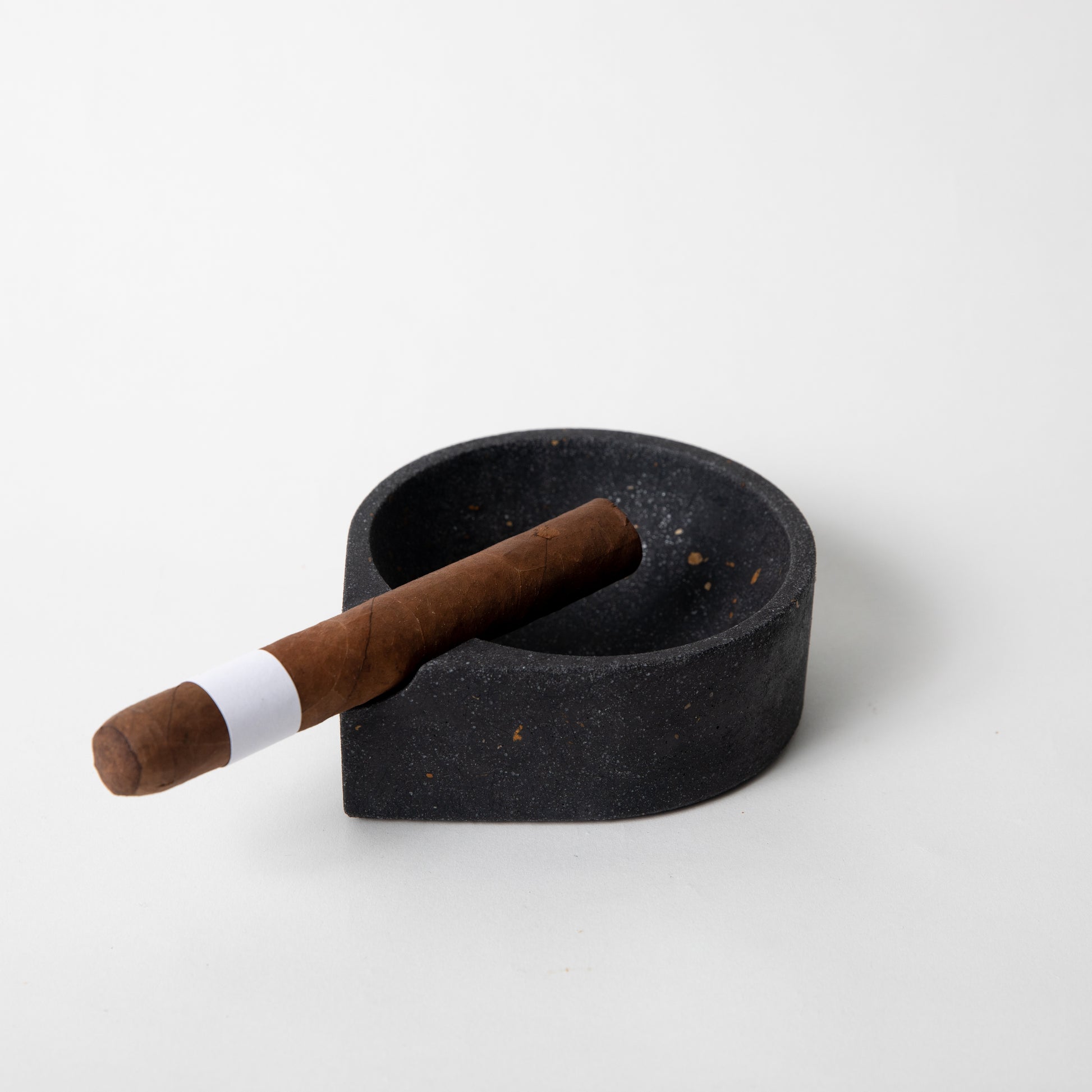 Black terrazzo ashtray w/ a cigar in it.