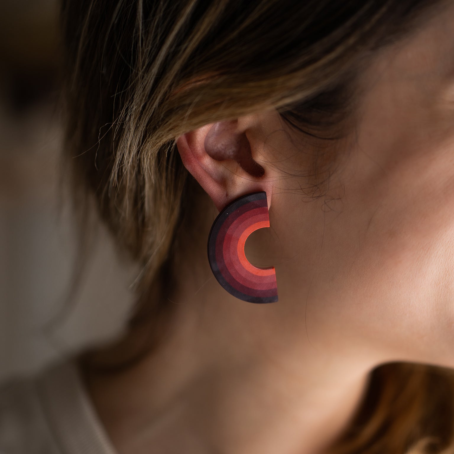 Earrings made from compressed paper with a titanium stud on model's ear.