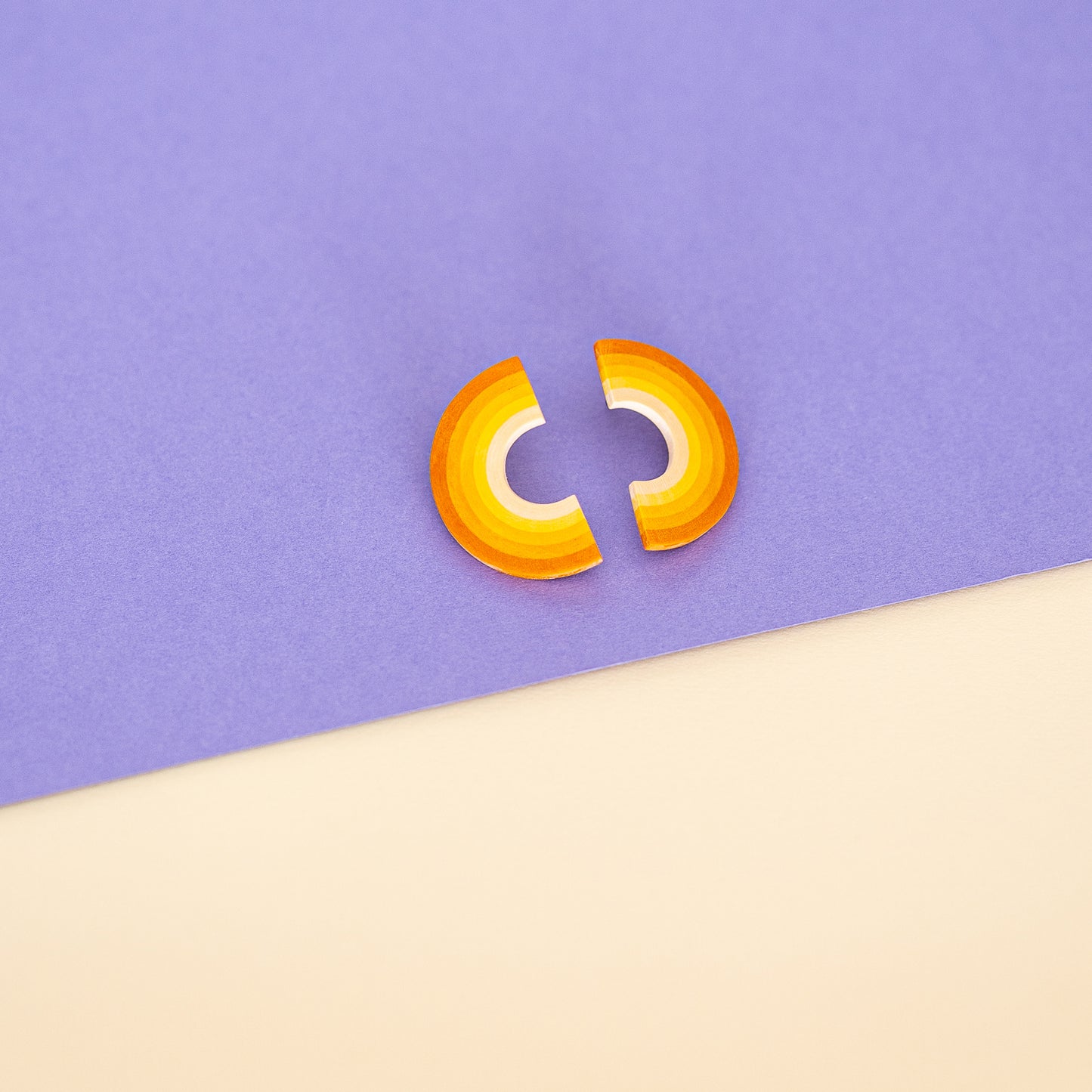Earrings made from compressed paper with a titanium stud in yellow and orange on colored paper.