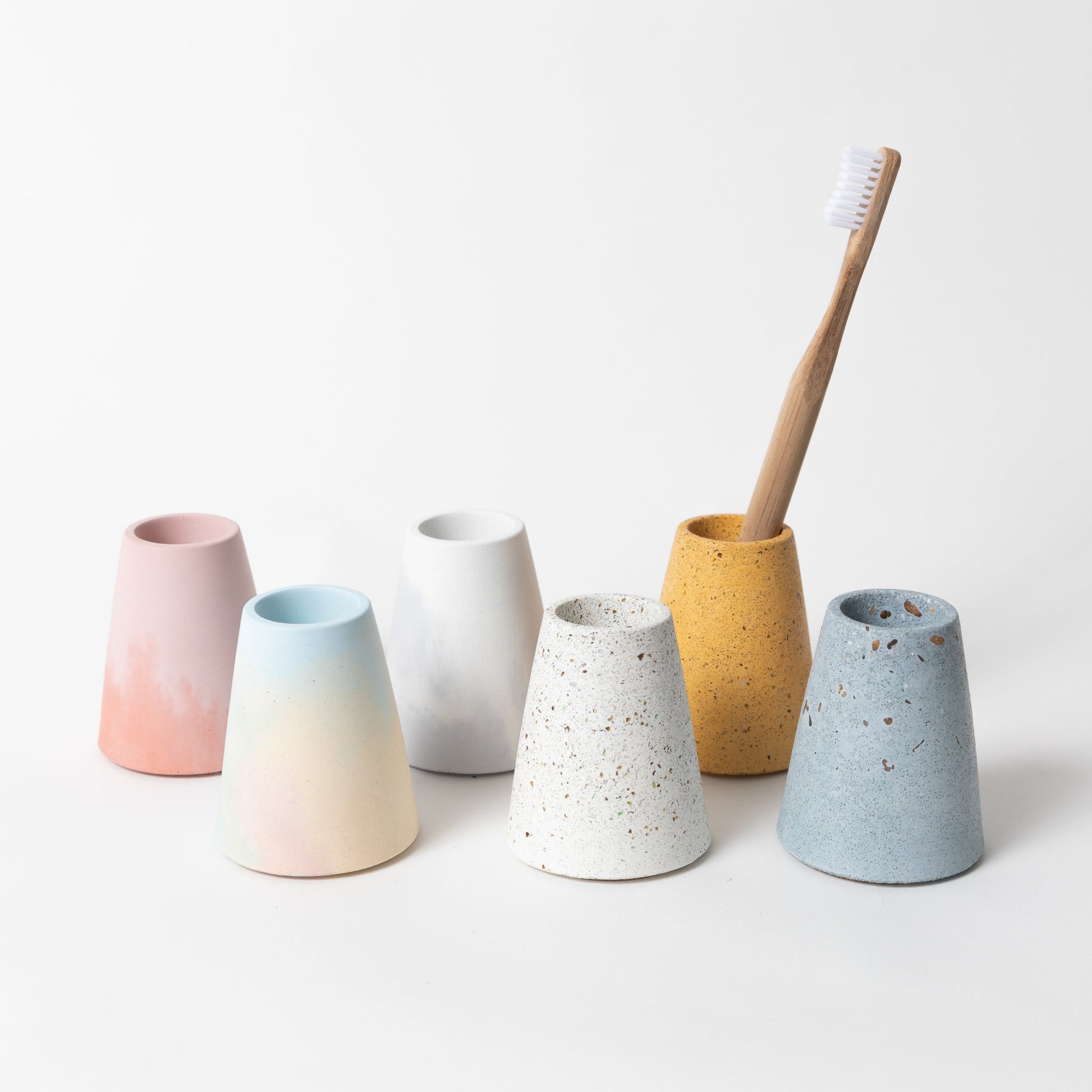 Concrete terrazzo toothbrush holder seen in various colors.