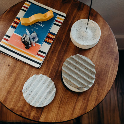 Greyscale terrazzo coaster set, sitting on a side table next to a white terrazzo incense dish and mango gloss pipe.