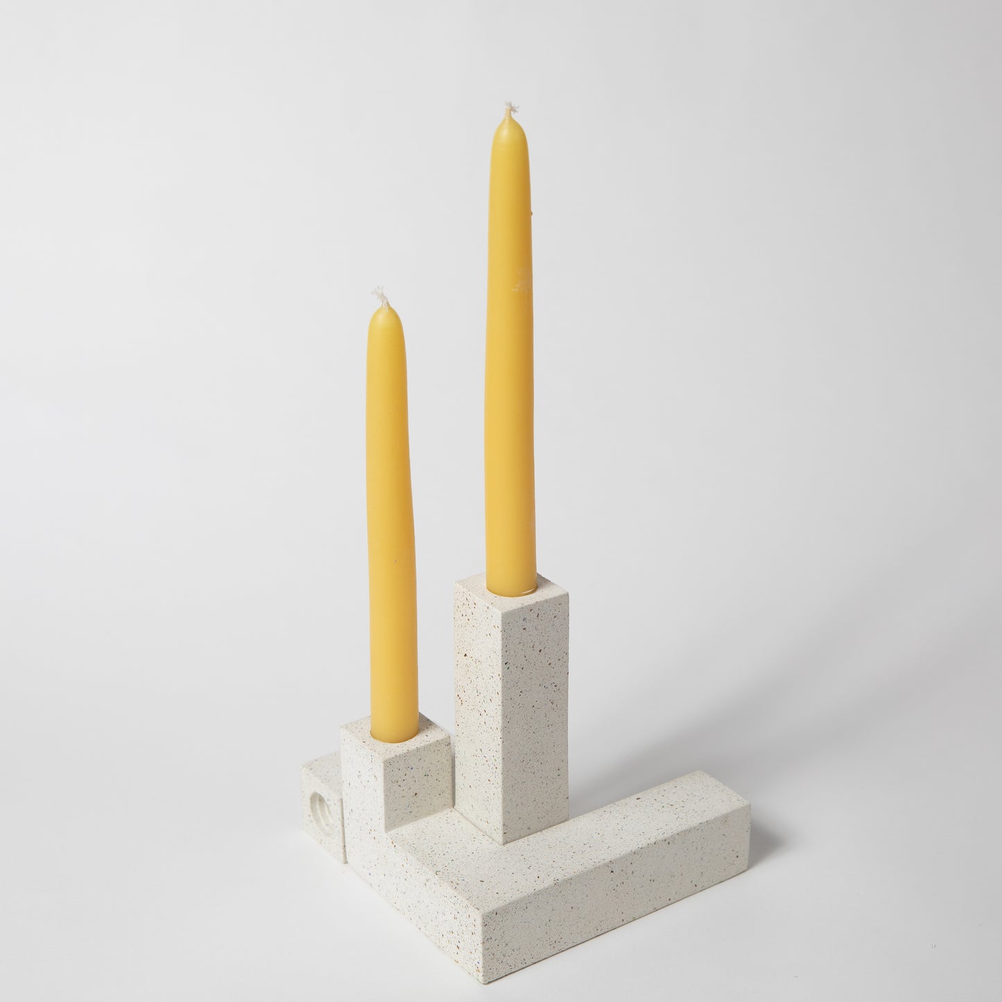 Concrete candlestick holder, set of 2 in white terrazzo holding candlesticks. Shows how they can fit together in fun way.