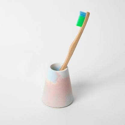 Concrete terrazzo toothbrush holder seen in jawbreaker(multicolored) with toothbrush.