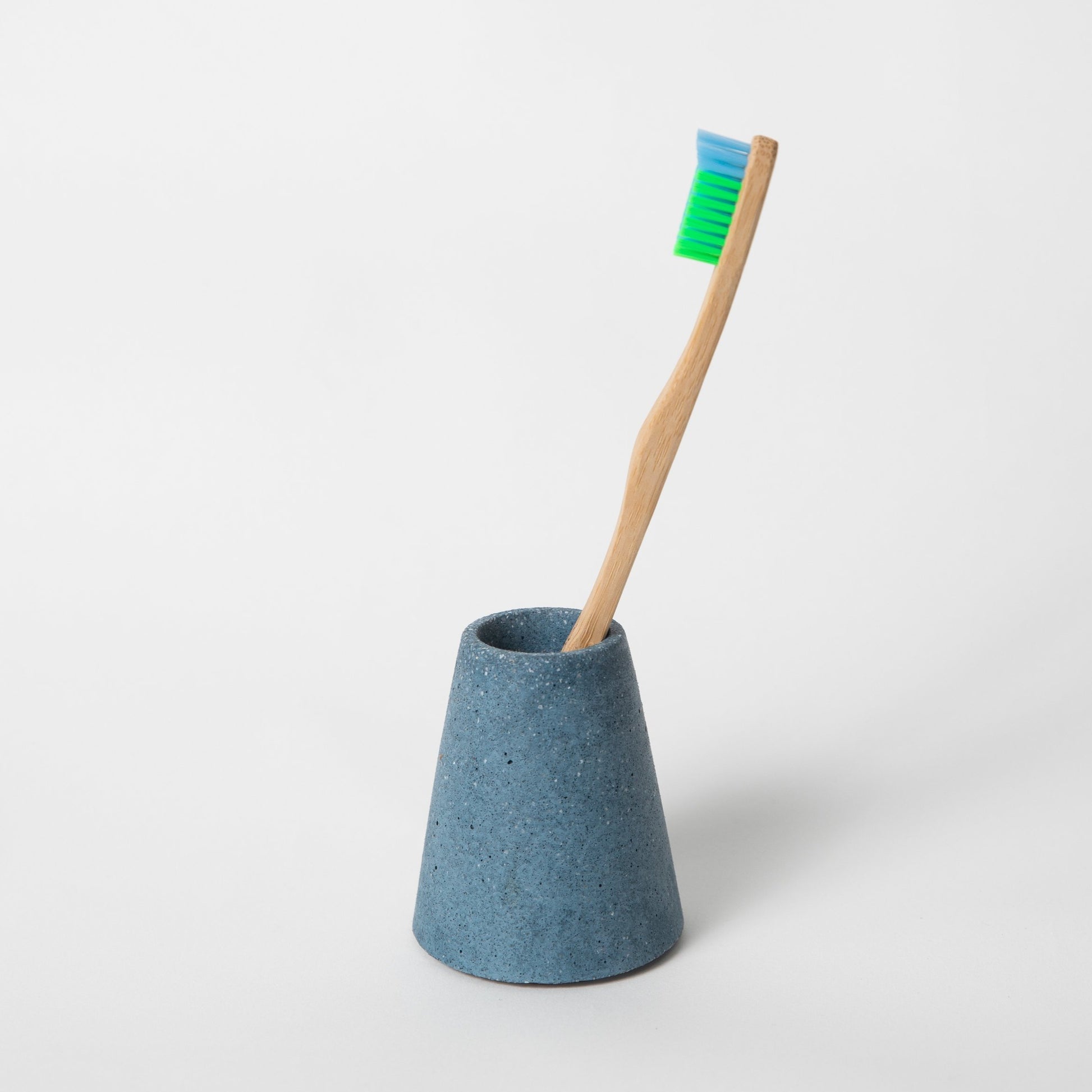 Concrete terrazzo toothbrush holder seen in cobalt terrazzo holding toothbrush.