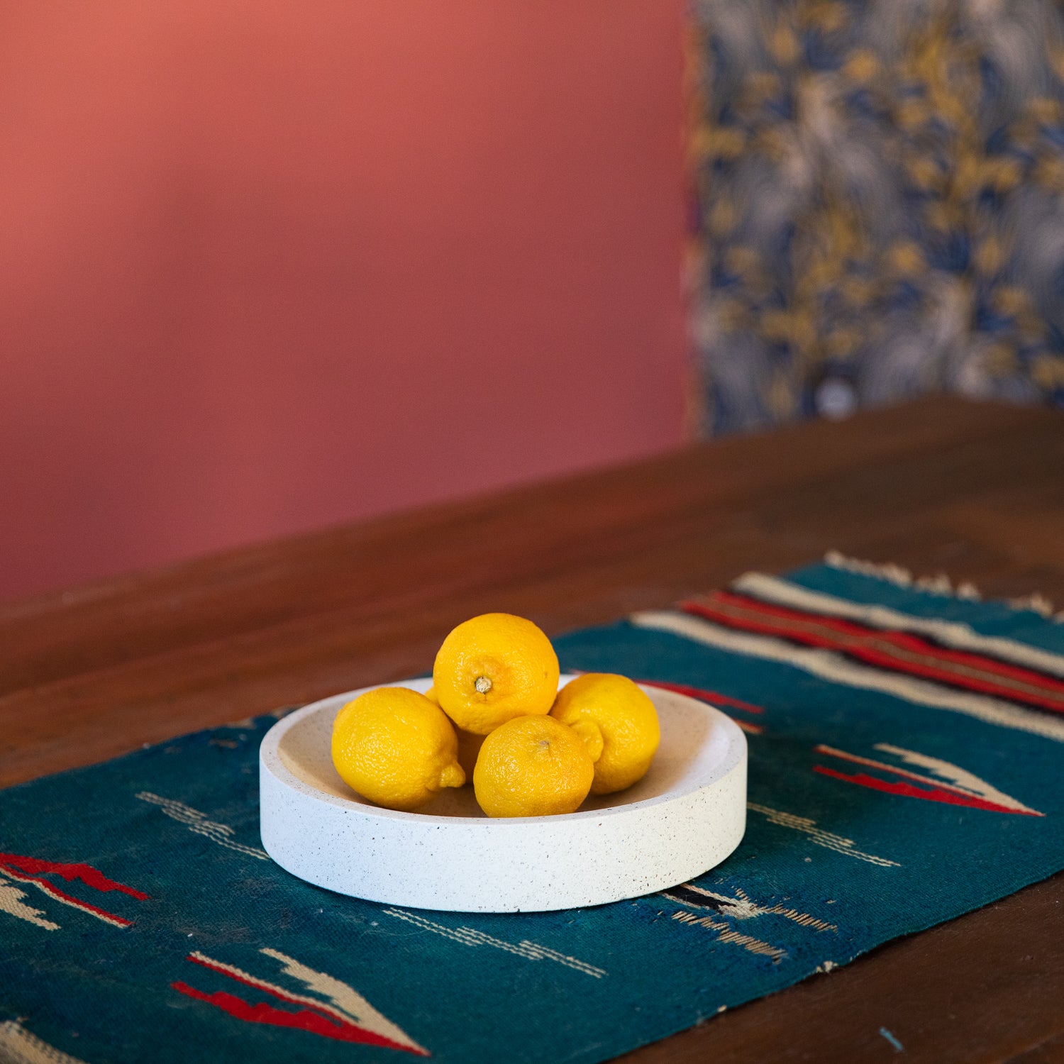 Large concrete centerpiece bowl in white terrazzo holding fruit on a table.