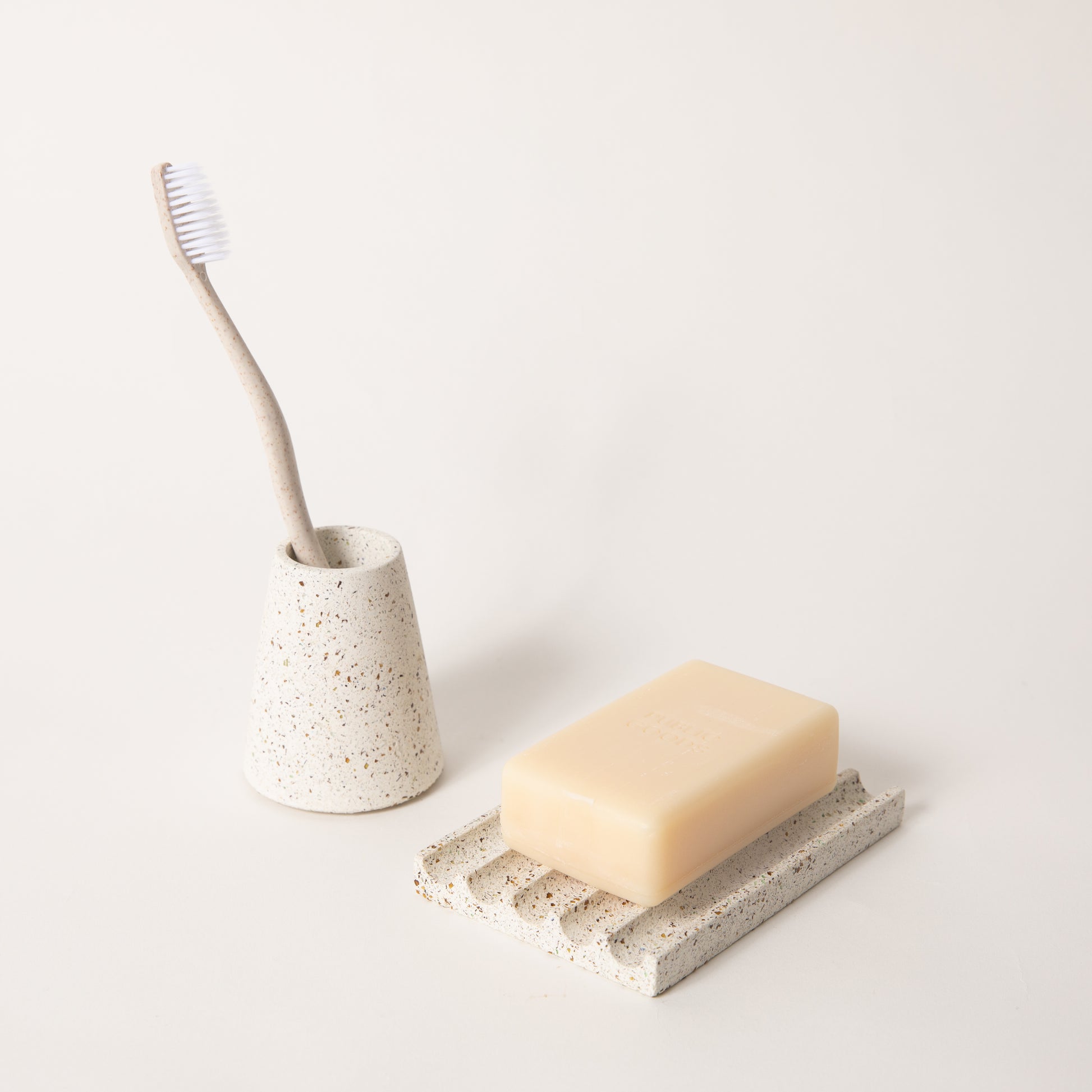 White terrazzo toothbrush holder & soap dish set, styled with a toothbrush & bar of soap.