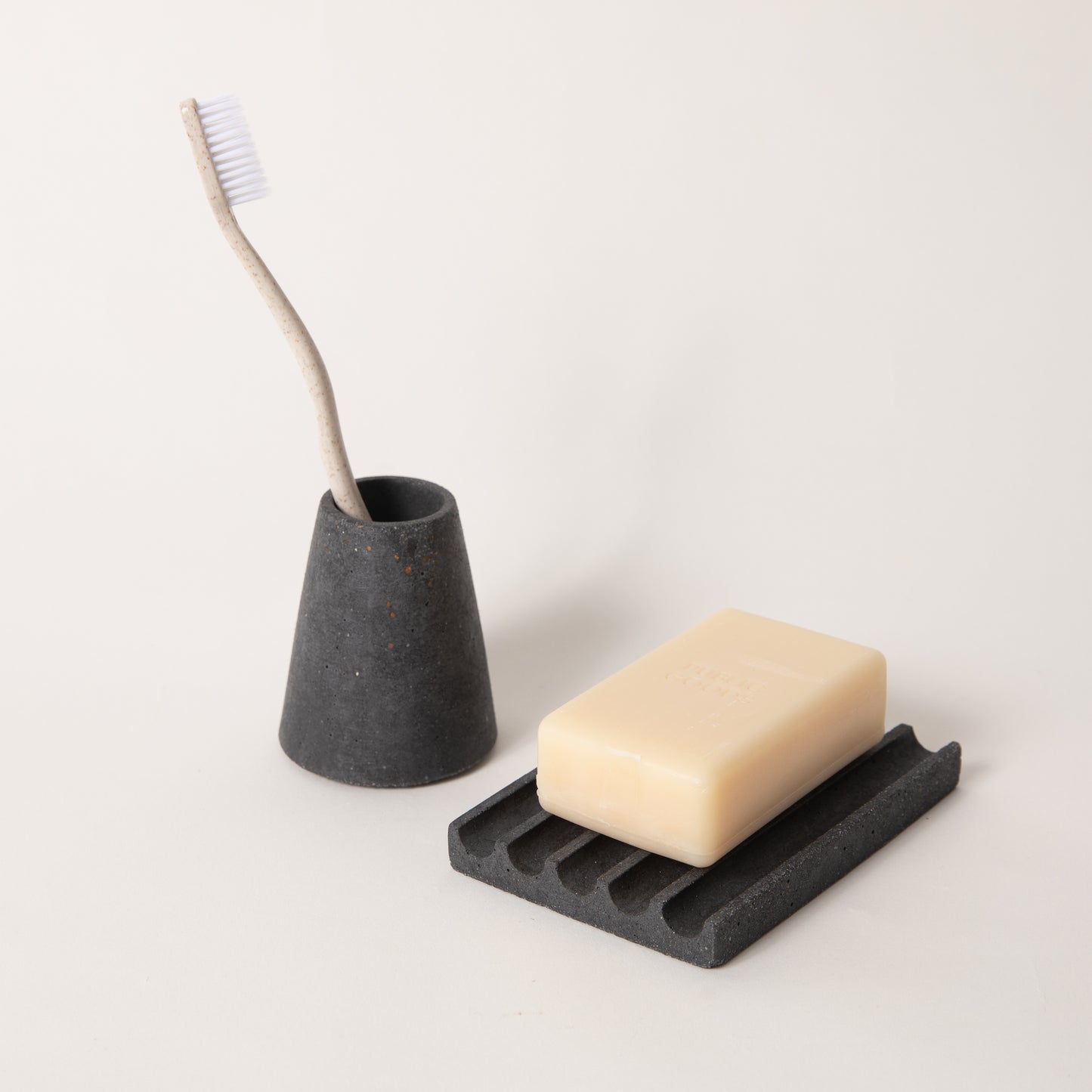 Black terrazzo toothbrush holder & soap dish set, styled with a toothbrush & bar of soap.