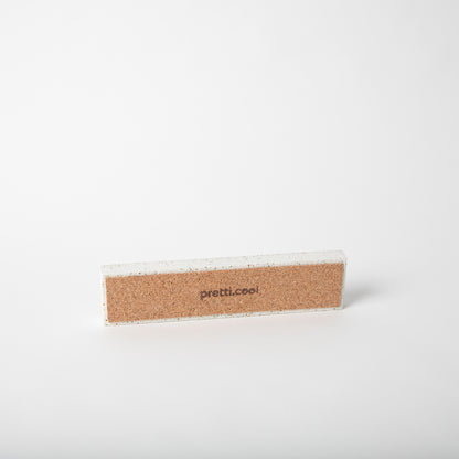 Concrete pencil tray in white terrazzo showing cork base.