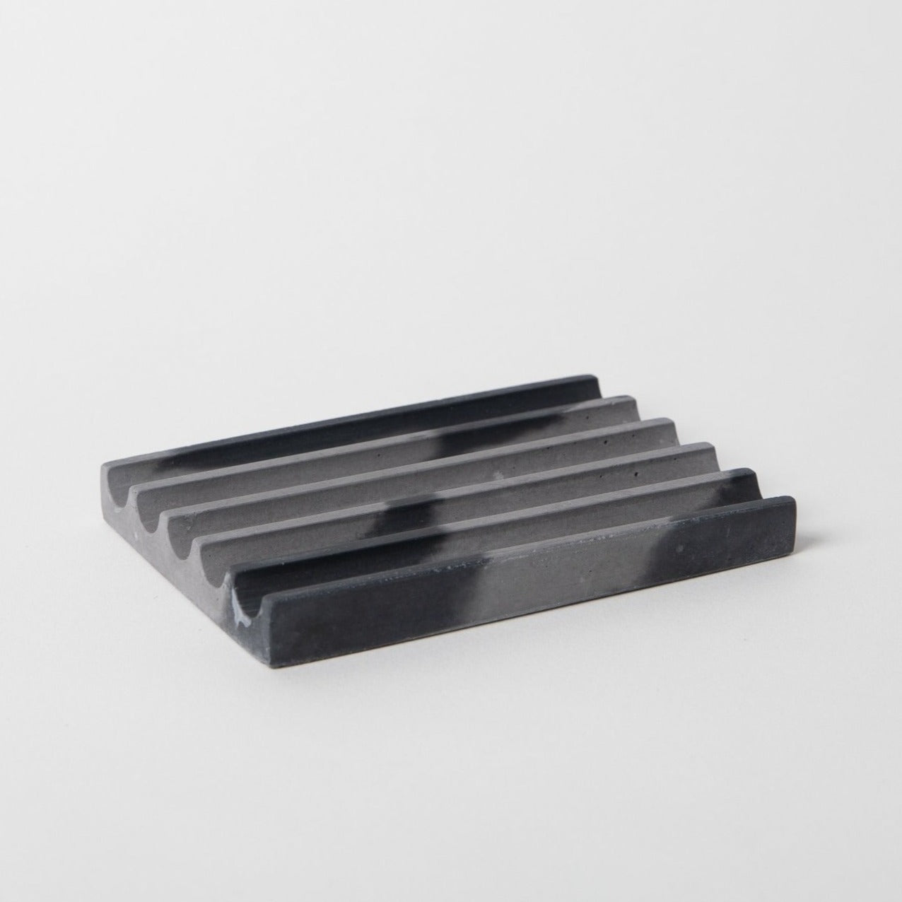 Concrete soap dish in black and grey.