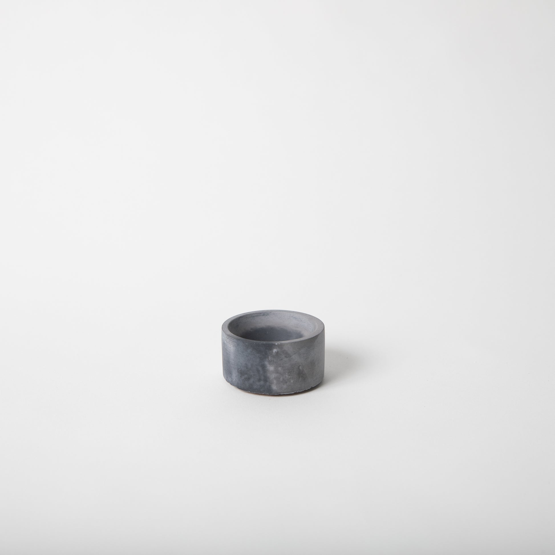 Round concrete incense holder in black and grey.