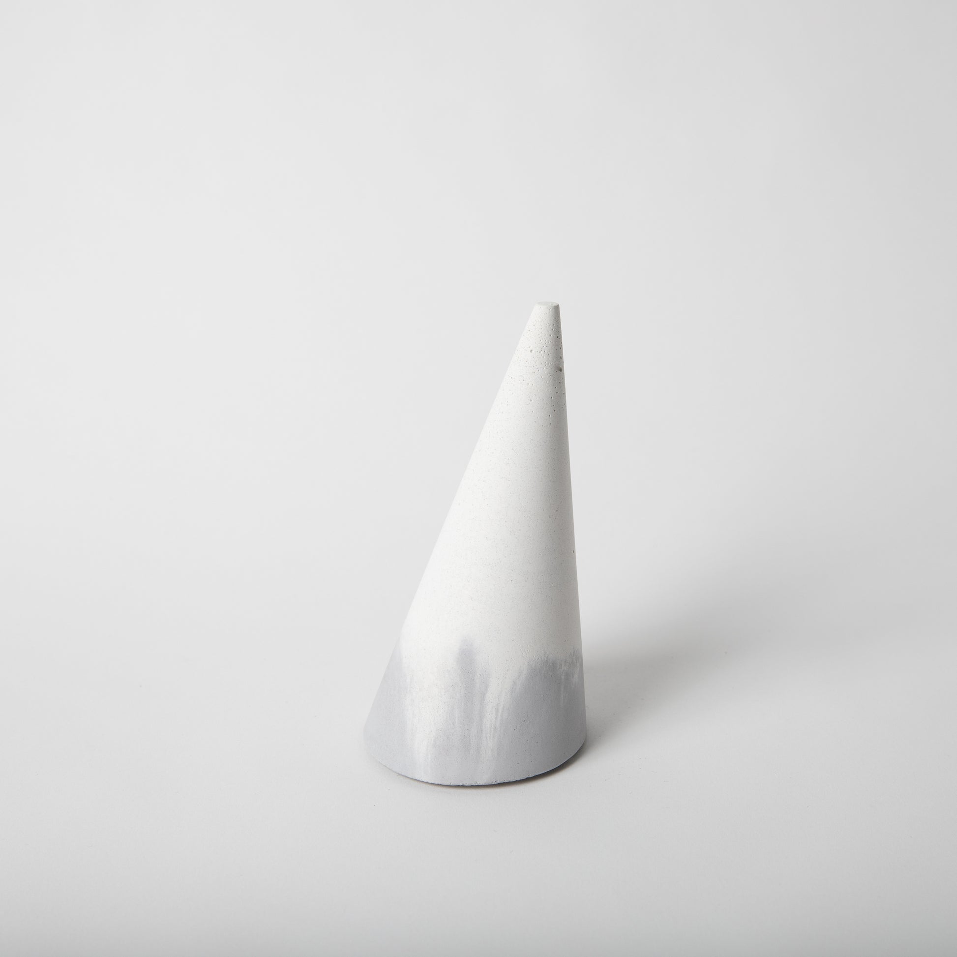 Cone shaped concrete bangle holder with cork base in grey and white.