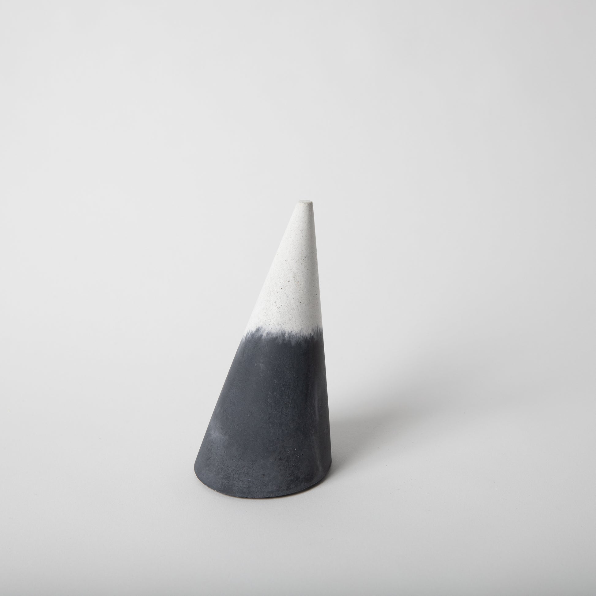 Cone shaped concrete bangle holder with cork base in black and white.
