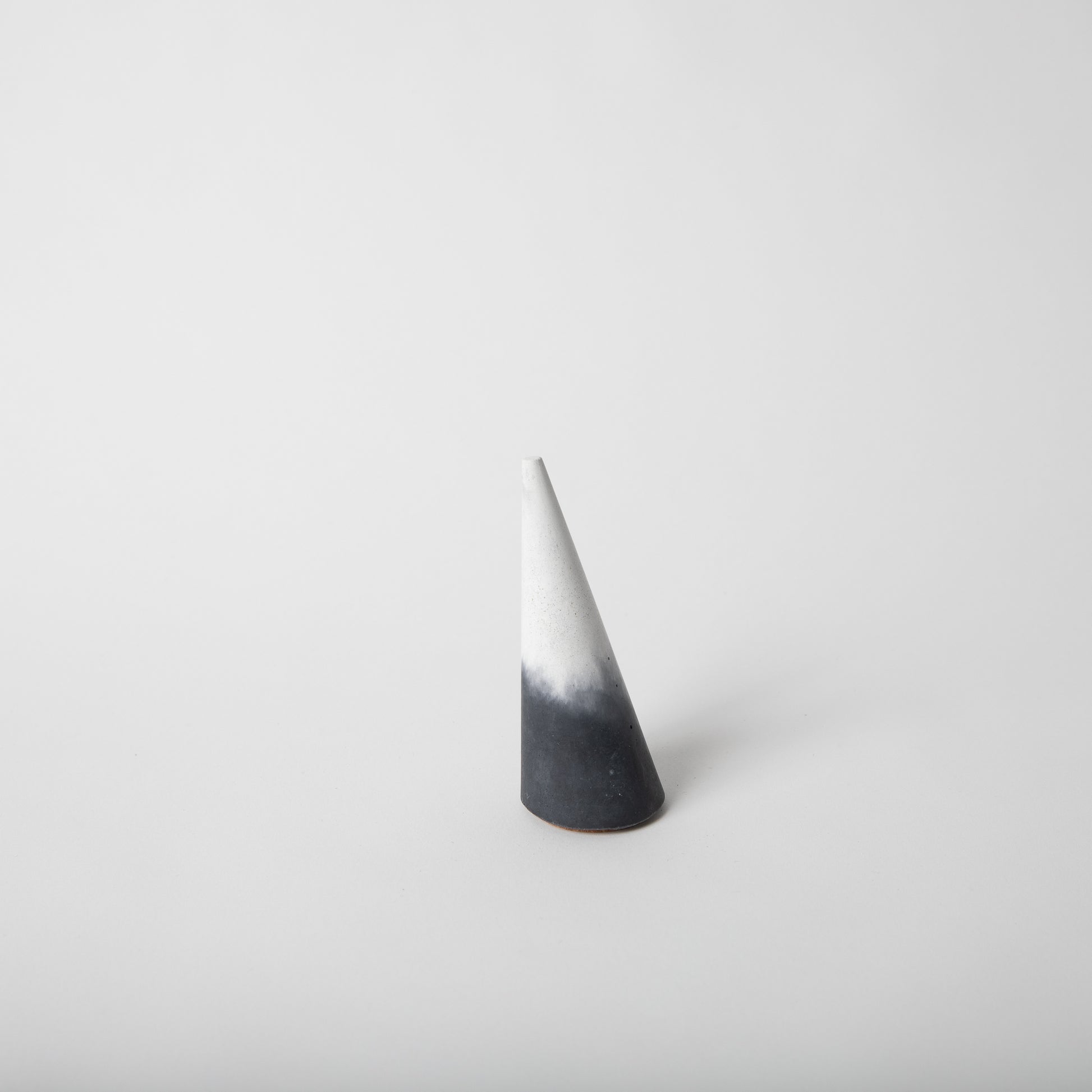 Cone shaped concrete ring holder with cork base in black and white.