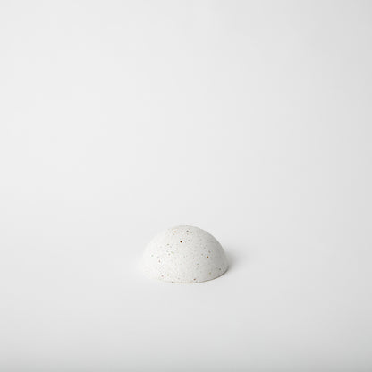 Half sphere shaped incense holder in white terrazzo.
