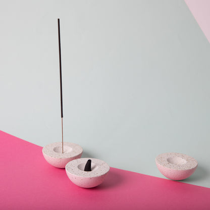 Half sphere shaped incense holder in white terrazzo. Shown holding incense.