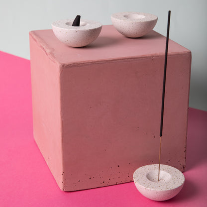 Half sphere shaped incense holder in white terrazzo. Shown holding incense, styled.