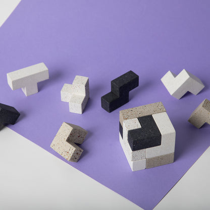 Concrete soma cube desk puzzle all 7 pieces laid out on colorful background.