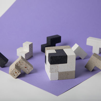 Concrete soma cube desk puzzle put together in front of separate pieces.