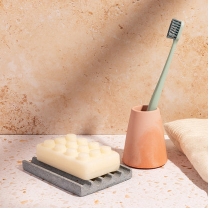 Our light blur terrazzo soap dish & coral/pink toothbrush holder, styled with a bar of soap, toothbrush, and a hand towel.